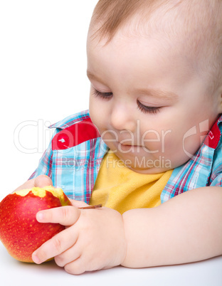 Little child is eating red apple