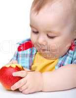 Little child is eating red apple