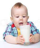 Cute little boy is going to drink milk from glass