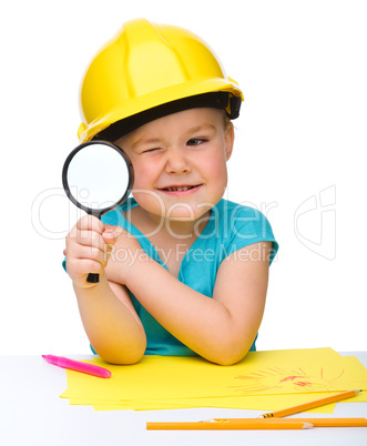 Cute little girl is looking through magnifier