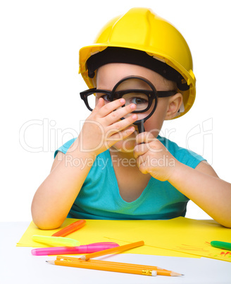 Cute little girl is looking through magnifier