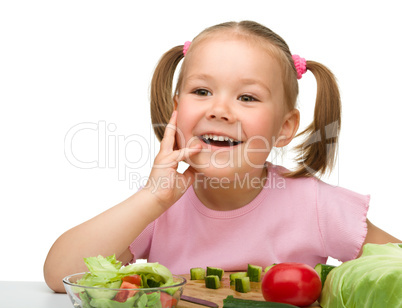 Little girl is cutting carrot for salad