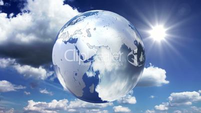 Spinning glass planet Earth on sky background