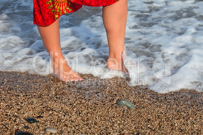 Naked woman legs in sea wave