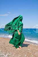 girl silhouette under green tissue on the sea beach