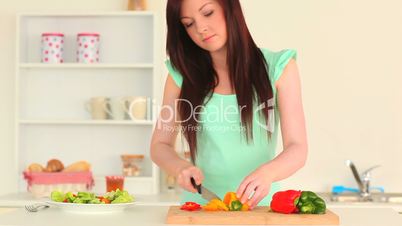 junge Frau schneidet Gemüse für Salat
