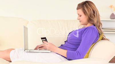junge Frau liegt auf der Couch mit Laptop