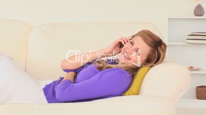 junge Frau liegt auf der Couch und telefoniert