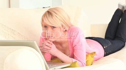 nachdenkliche junge Frau vor Laptop auf der Couch