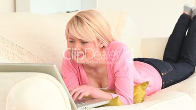 junge Frau liegt auf der Couch mit Laptop