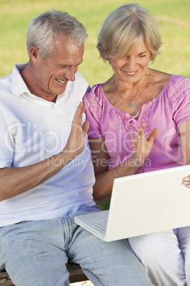 Happy Senior Couple Using Laptop Computer Outside in Sunshine