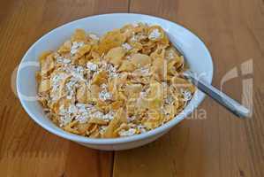 White bowl with a spoon, corn and oats flakes