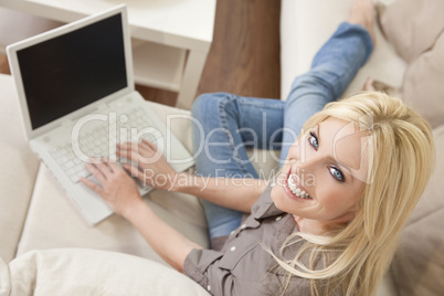 Young Blond Woman Using Laptop Computer At Home on Sofa