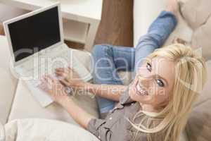 Young Blond Woman Using Laptop Computer At Home on Sofa