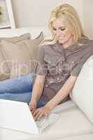 Young Blond Woman Using Laptop Computer At Home on Sofa