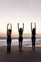 Three Women Practicing Yoga on Beach At Sunrise or Sunset