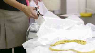 Wedding dress: young hispanic female dressmaker cutting white fabric