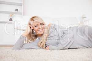 Attractive blond woman talking on cell phone lying down on a car