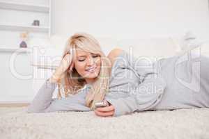 Attractive blond woman playing with cell phone lying down on a c