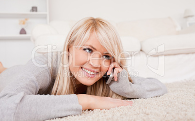 Attractive smiling blond woman talking on cell phone lying down