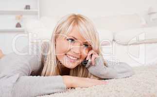 Attractive smiling blond woman talking on cell phone lying down