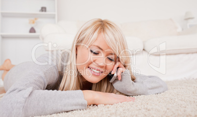 Attractive blond woman talking on cell phone lying down on a car