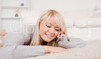 Attractive blond woman talking on cell phone lying down on a car