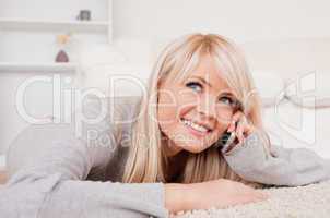 Beautiful happy blond woman talking on cell phone lying down on