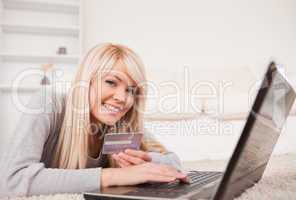 Beautiful relaxed woman relaxing on laptop lying on a carpet