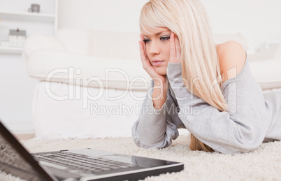 Attractive concentrated woman relaxing on laptop lying on a carp