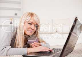 Pretty relaxed woman relaxing on laptop lying on a carpet