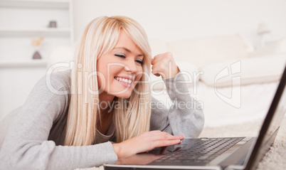 Attractive relaxed woman relaxing on laptop lying on a carpet
