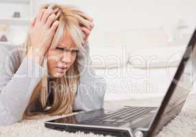 Attractive blond woman frustrated with her computer lying on a c