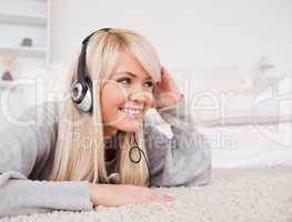 Attractive blond woman with headphones lying on a carpet