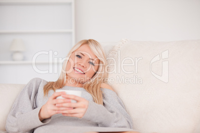 Gorgeous blond woman lying on a sofa relaxing on a line of table