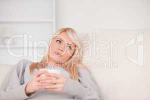 Attractive blond woman lying on a sofa relaxing on a line of tab
