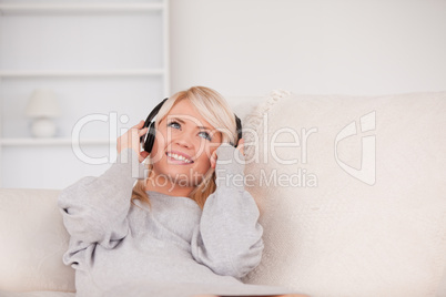 Attractive blond woman with headphones lying in a sofa