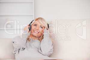 Attractive blond woman with headphones lying in a sofa