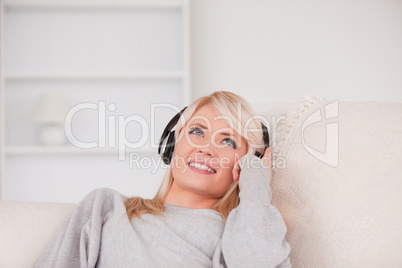 Pretty blond woman with headphones lying in a sofa