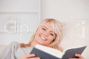Junge blonde Frau lächelt und liest ein Buch