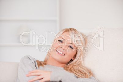 Junge blonde Frau auf dem Sofa mit verschränkten Armen