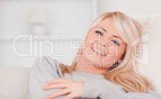 Junge blonde Frau auf dem Sofa mit verschränkten Armen