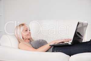 Beautiful woman relaxing on laptop lying on a sofa