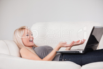 Joyful woman relaxing on laptop lying on a sofa