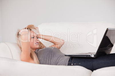 Attractive blond woman frustrated with her computer lying on a s