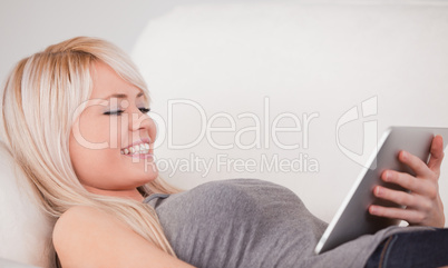 Attractive woman lying on a sofa relaxing on a line of tablet co