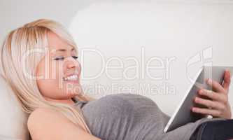 Attractive woman lying on a sofa relaxing on a line of tablet co