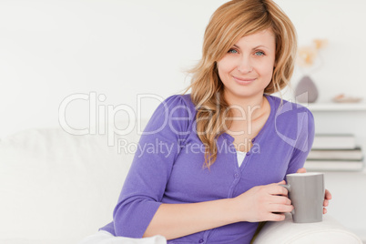 Beautiful red-haired woman holding a cup of coffee while sitting