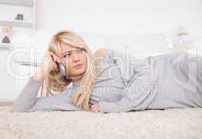 Beautiful blond woman talking on cell phone lying down on a carp