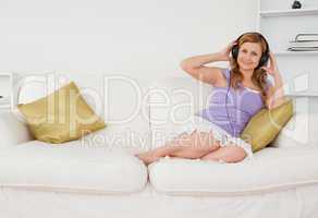Smiling beautiful woman listening to music and posing while sitt